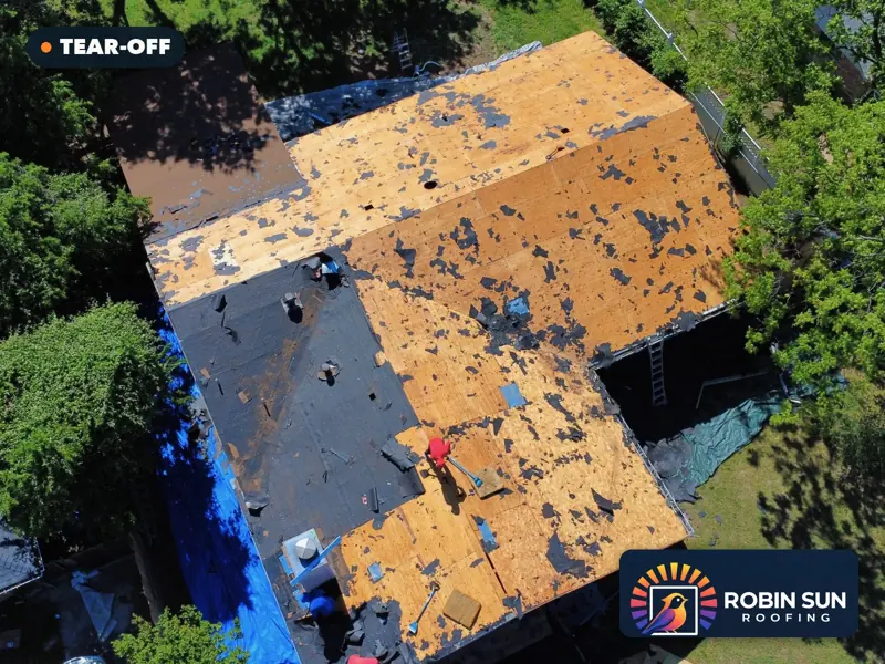 Drone view of the same roof stripped to the wood decking, crew on the roof.