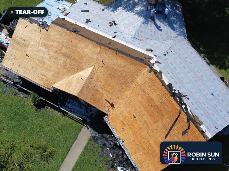 Drone view of bare wood decking on one side of the roof and new underlayment on the other.