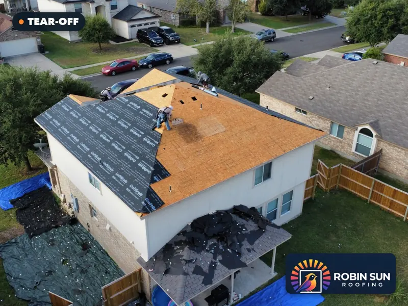 Drone view of a two-story house with the roof stripped to the decking and underlayment going on.
